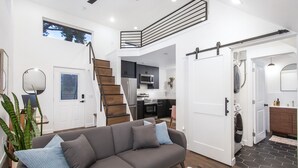 A modern apartment with a grey sofa, a staircase, a kitchen, and a laundry area. - Private guest house, king bed, work-from-home friendly, fully equipped kitchen (Denver)