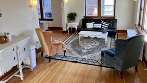 A living room with a black sofa, a white coffee table, a patterned rug, a brown armchair, and a white dresser. - Charming & convenient house in downtown Marshall (Marshall)