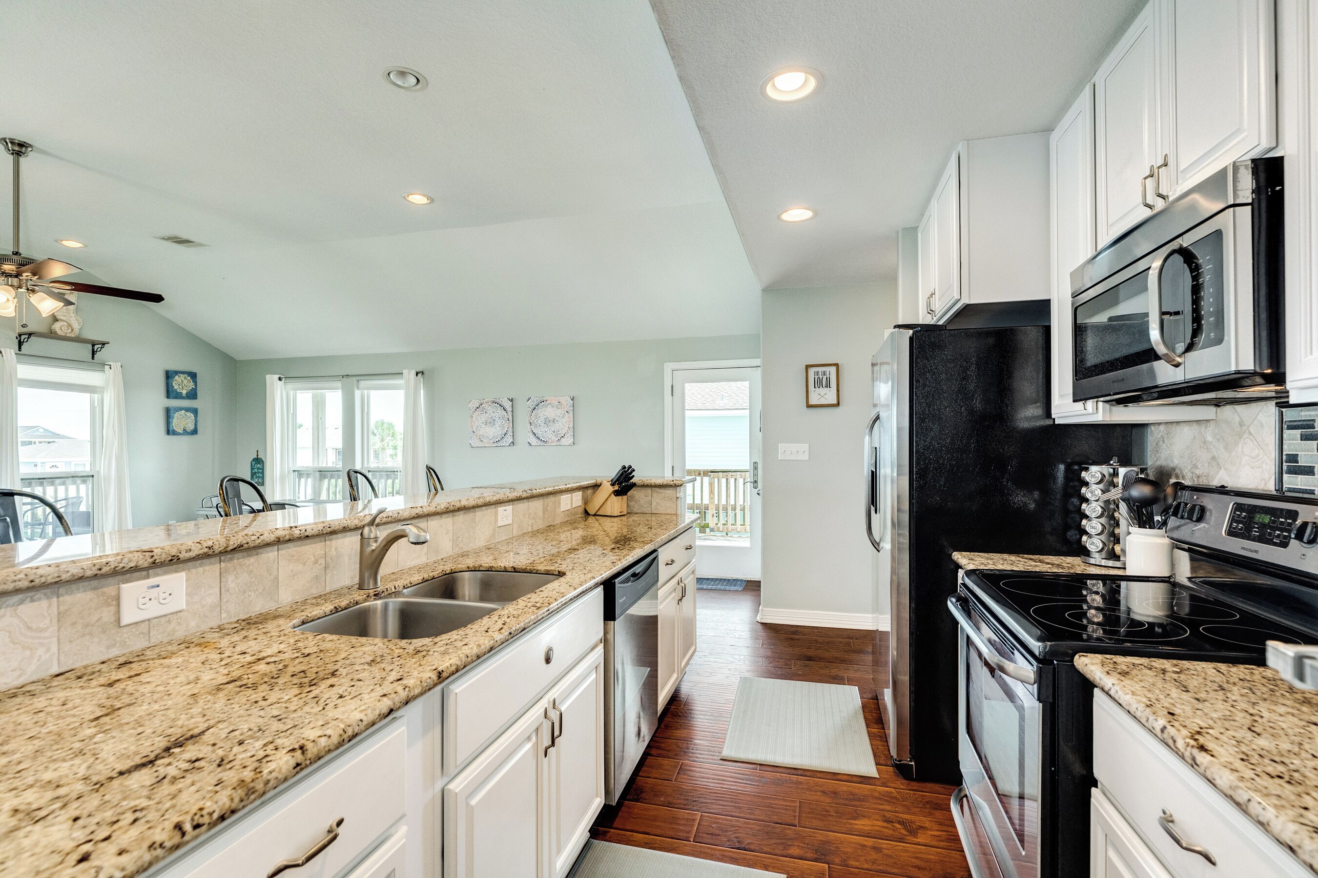 A kitchen with granite countertops, stainless steel appliances, and white cabinetry.