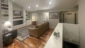A living room with a fireplace, a sofa, a coffee table, and a bookshelf. - Willow Creek Oasis with Amazing Outdoor Kitchen (Centennial)
