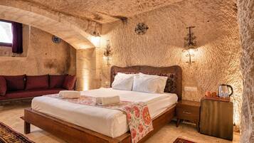 Un dormitorio con pared de piedra, una cama de madera, una mesita de noche y una ventana con cortinas.