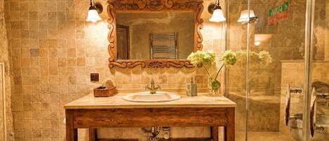 Une salle de bain avec un meuble-lavabo en bois, un grand miroir et une cabine de douche en verre.