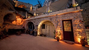 Een gebouw van steen met een houten deur, gebogen ramen en een balkon met parasols.