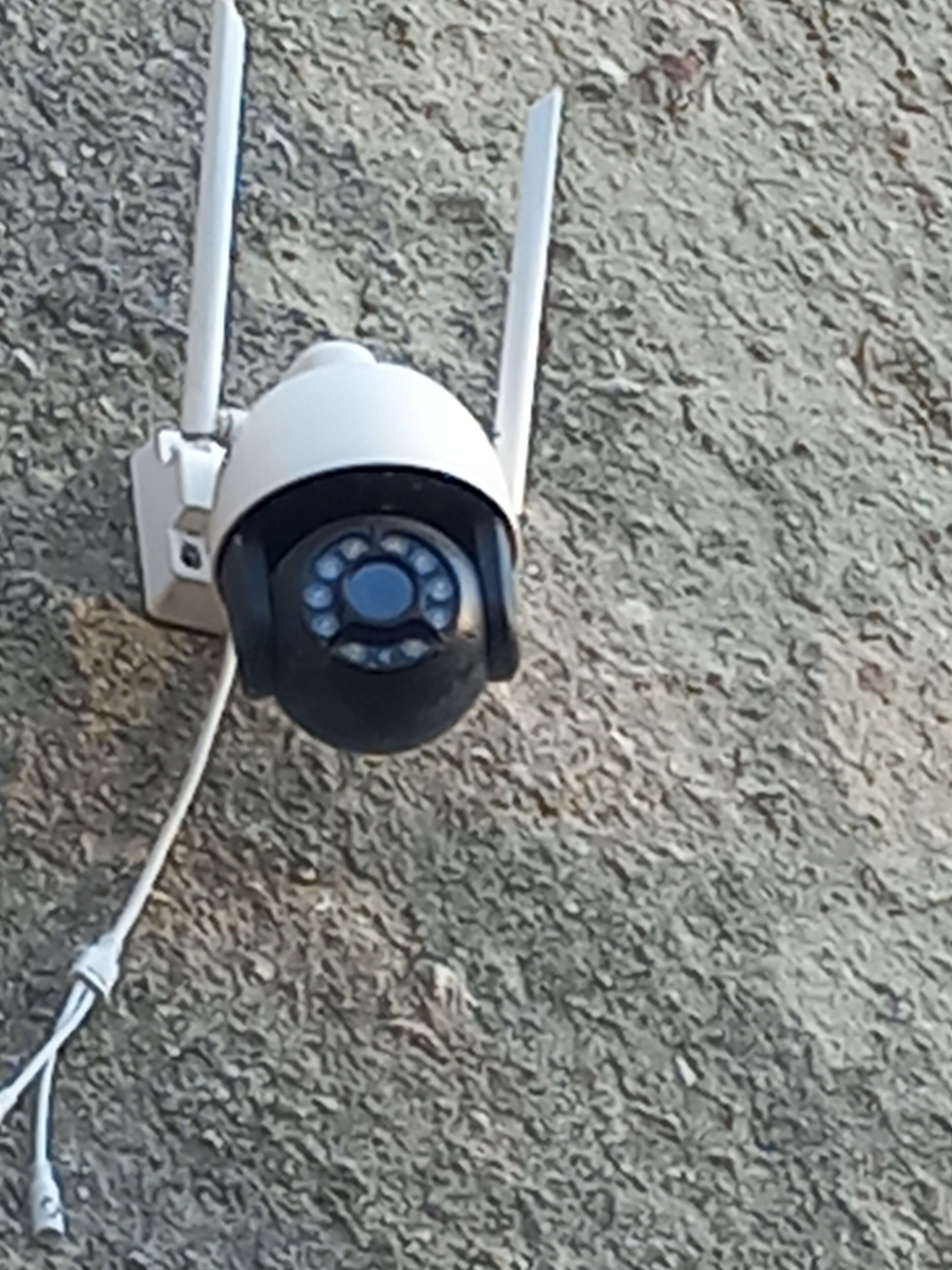 A security camera mounted on a textured wall.