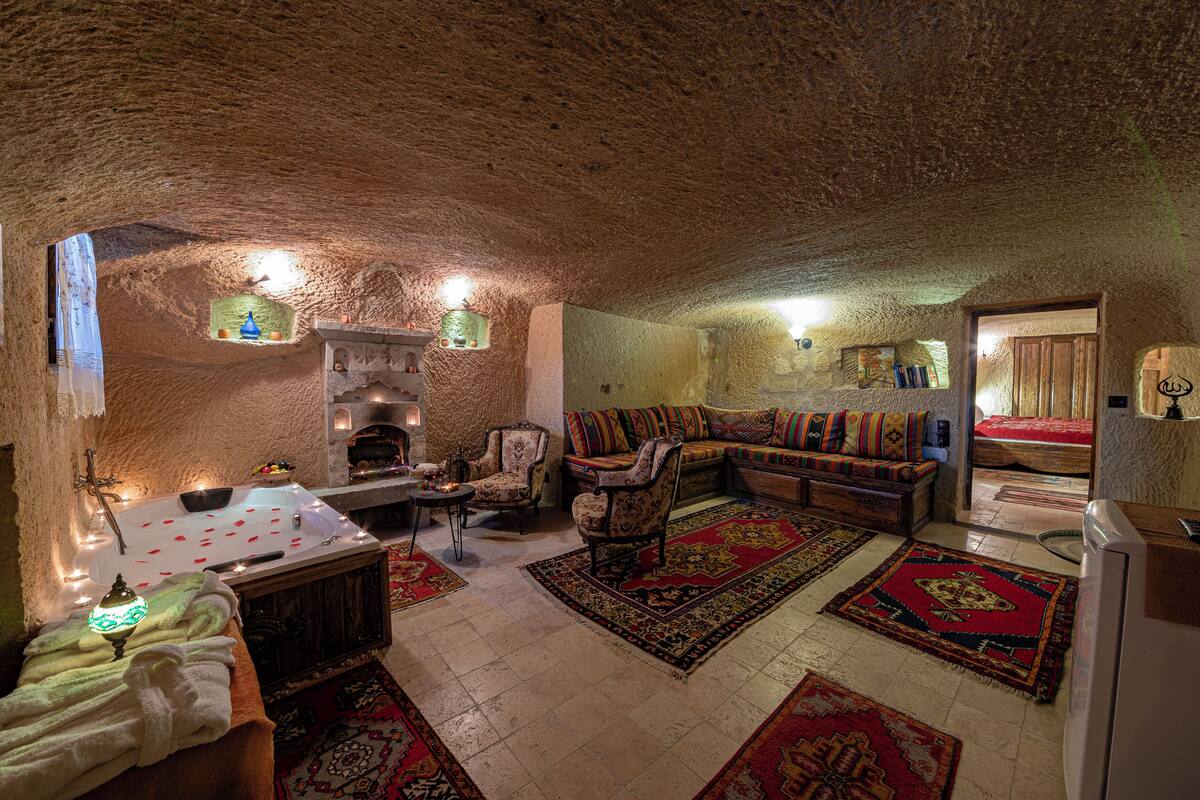 Um interior acolhedor e rústico com teto de pedra, lareira, sofás e uma área de refeições com mesa e cadeiras.