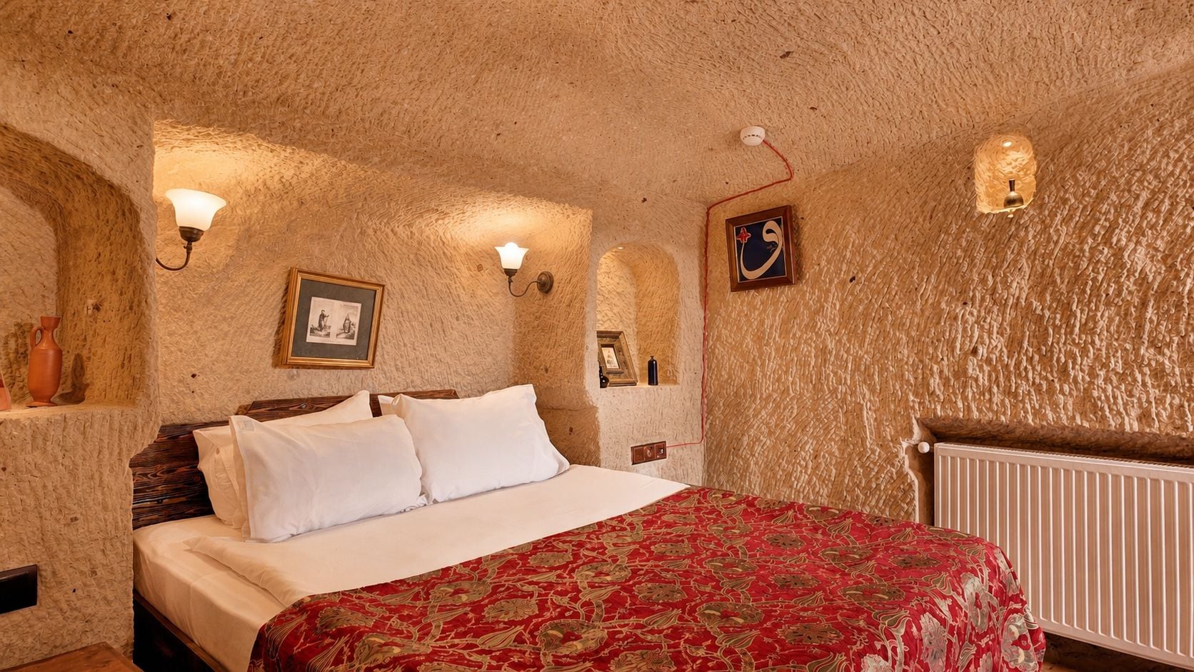 A room with a bed, a radiator, and wall-mounted lights.