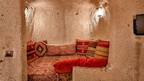 Una habitación acogedora con pared texturizada, un sofá con cojines estampados y una lámpara de pared.