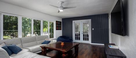 A spacious living room with a white sofa, a wooden coffee table, and a ceiling fan.