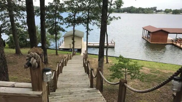 A wooden staircase leading to a dock over a lake, with a small building in the background. - Lakehouse Getaway! (Pittsburg)