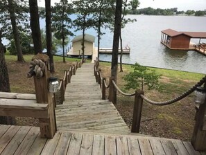 A wooden staircase leading to a dock over a lake, with a small building in the background. - Lakehouse Getaway! (Pittsburg)