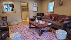 A cozy living room with a brown leather sofa, a wooden coffee table, and a patterned rug. - White mountain getaway (Carroll)