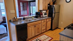 A kitchen with wooden cabinets, a dishwasher, a refrigerator, and a microwave. - White mountain getaway (Carroll)