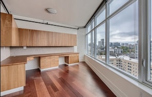 Enjoy a city view from the kitchen's large windows, featuring a sleek countertop and wooden cabinetry.