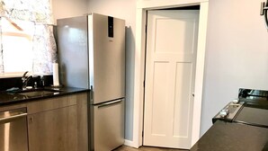 A compact kitchen with a stainless steel refrigerator, a wooden cabinet, and a black countertop. - Relaxing Scenic 1 Bedroom Retreat With Private Hot Tub (Findlay)
