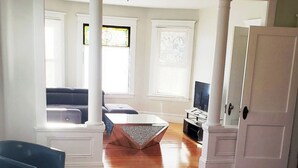 A spacious living room with hardwood flooring, a coffee table, a sofa, and a television. - Bright and cozy 3 bedroom apartment in Chicopee with AC, WiFi. Enjoy your stay (Chicopee)