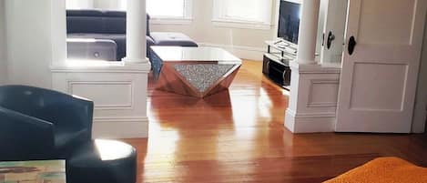 Un salón amplio con piso de madera, una mesa de centro, un sofá y un televisor.