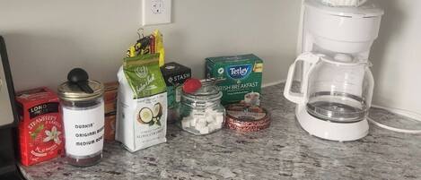 A kitchen counter with various food items and a coffee maker.
