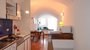 Eine kompakte Küche mit Herd, Spüle und einem Essbereich mit Tisch und Stühlen.
