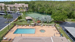 A hotel with a swimming pool, tennis court, and a parking lot. - Newly updated 2br2br+Den golf course property near airport 90-day min stay (Fort Myers)