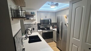 A modern kitchen with a skylight, stainless steel appliances, and a white countertop. - Newly updated 2br2br+Den golf course property near airport 90-day min stay (Fort Myers)