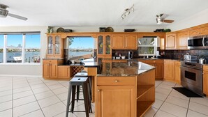 A kitchen with wooden cabinets, a granite countertop, a stainless steel oven, and a view of the marina.
