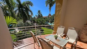 A balcony with a table and chairs, overlooking a pool and garden area. - Nice 2 bedroom Apt. in Ocean Dream (Cabarete)