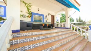 A staircase with patterned tiles leading to a covered outdoor area with seating and decorative plates on the walls. - Finca Real de Niebla by Ruralidays (Huelva)