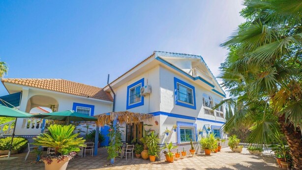 A two-story house with a tiled roof, blue trim, and multiple windows. - Finca Real de Niebla by Ruralidays (Huelva)