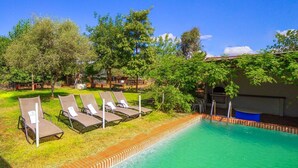 A swimming pool with lounge chairs and a building in the background. - Finca Real de Niebla by Ruralidays (Huelva)