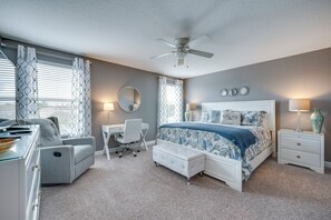 Ein Schlafzimmer mit Bett, Schreibtisch, Stuhl und Deckenventilator.