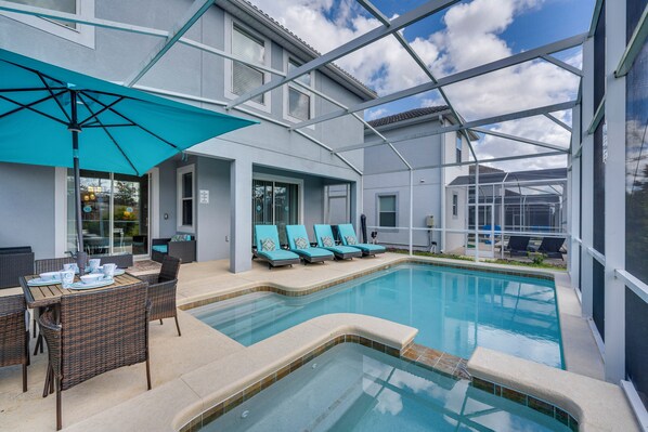 Ein Poolbereich mit Liegestühlen und einem Tisch, umgeben von einer überdachten Terrasse.