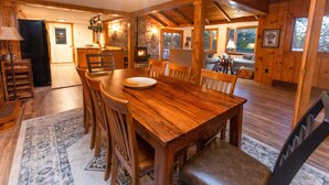 Una mesa de madera para comer con sillas, una chimenea de piedra y una zona de estar acogedora con un sofá y una lámpara.