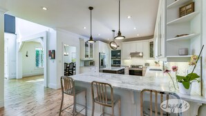 A modern kitchen with a large island, bar stools, and pendant lighting. - Tranquil 4 bed 4 bath home in Collingwood (Collingwood)