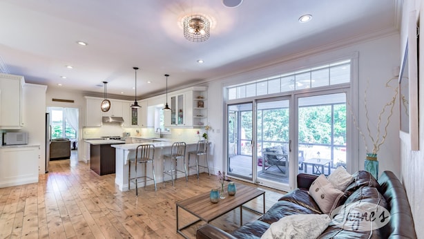 A spacious kitchen with a central island, bar stools, and a dining area with a view of the outdoors. - Tranquil 4 bed 4 bath home in Collingwood (Collingwood)