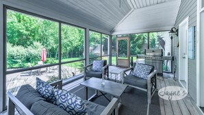 A covered outdoor patio with a wooden ceiling, large windows, and a grill area. - Tranquil 4 bed 4 bath home in Collingwood (Collingwood)