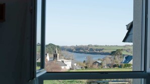 A view through a window of a rural landscape with a body of water, buildings, and greenery. - Penn Ar Roz - Large house Pwd access near the sea (Saint-Pabu)