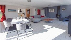 A modern living room with a dining area, grey sofa, and a fireplace. - Penn Ar Roz - Large house Pwd access near the sea (Saint-Pabu)