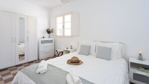 A bedroom with a bed, white wardrobe, bedside table, and a hanging light fixture.