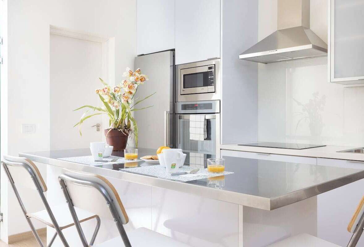 Una cocina moderna con una isla central, electrodomésticos de acero inoxidable y una planta en maceta.