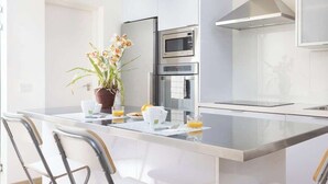 A modern kitchen with a central island, stainless steel appliances, and a potted plant.