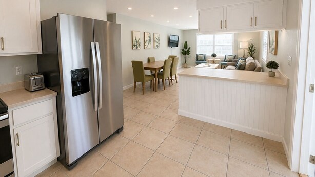 A modern kitchen with a stainless steel refrigerator, a dining area with a table and chairs, and a small island with a sink. - Welcome to your Indian Rocks Beach getaway! This bright, newly refreshed 4-bed, 2-bath home sleeps up to 12, features a sun-heated pool just outside your door, and is only a 2-minute walk to beach access, local cafes, and ice cream shops.  *2nd floor (Indian Rocks Beach)