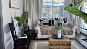 Un salon avec un canapé, une table basse, un fauteuil et une grande plante.