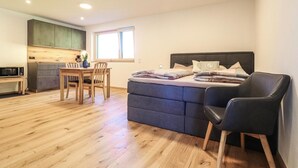 Eine kompakte Studio-Ferienwohnung mit Küchenzeile, Essbereich und Bett mit Kopfteil.