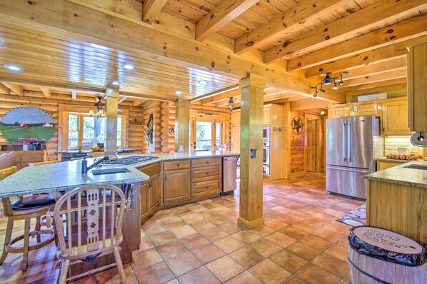 A spacious kitchen with wooden beams, a large island, and stainless steel appliances. - Calhoun Cabin w/ River View + Wraparound Deck (Calhoun)