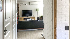 A modern living room with a flat-screen TV, a sofa, a coffee table, and a bookshelf.