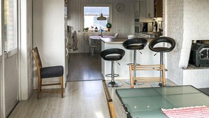 A compact kitchen with a dining area, featuring a wooden dining table, four bar stools, and a single chair.