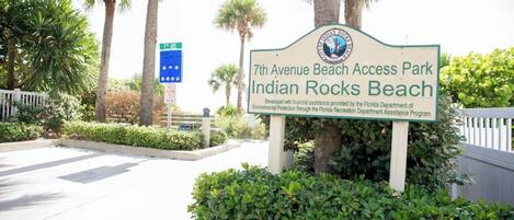 A sign for 7th Avenue Beach Access Park Indian Rocks Beach with a landscaped entrance and palm trees.