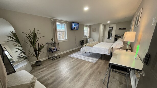 A modern hotel room with a bed, a desk, a chair, a TV, and a window.