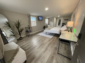 Een moderne hotelkamer met een bed, een bureau, een stoel, een televisie en een raam.