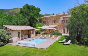Une villa en pierre dotée d’une piscine, d’un espace extérieur aménagé et d’une végétation luxuriante.